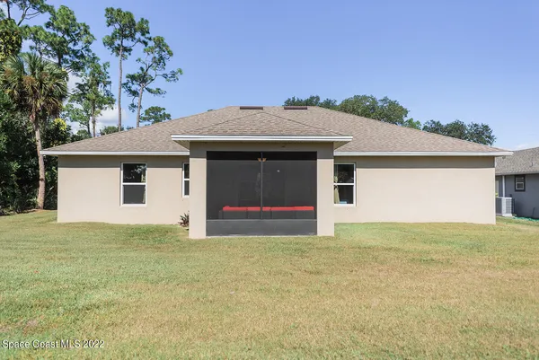 a view of an house with backyard and a tree