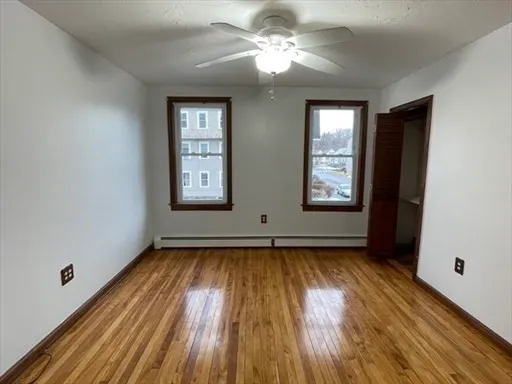 a view of an empty room with window and wooden floor