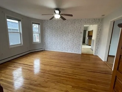 a view of an empty room with window and wooden floor