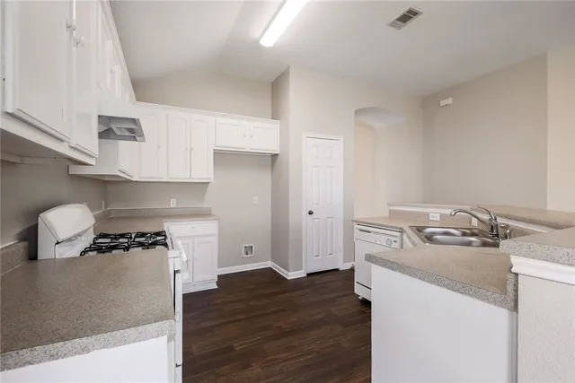 a kitchen with a stove and wooden floor