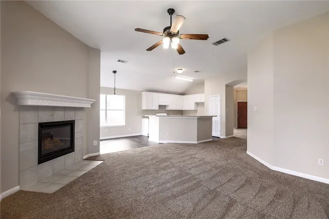 a view of kitchen and empty room with fireplace