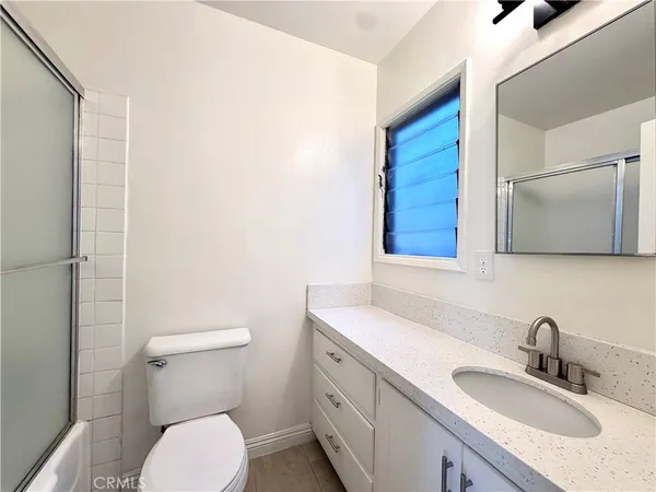 a bathroom with a granite countertop toilet sink and mirror