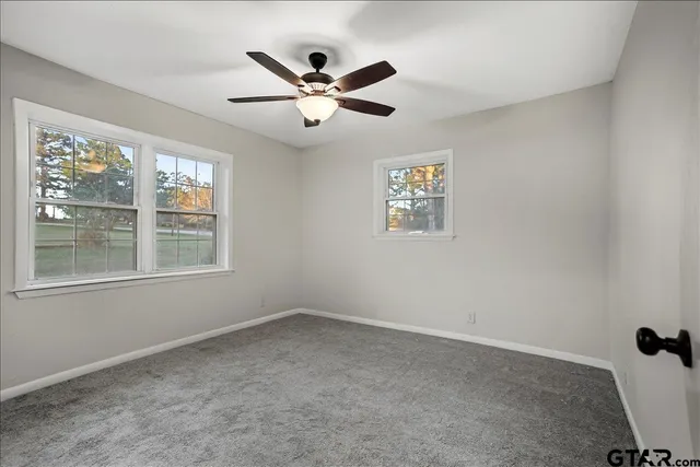 an empty room with ceiling fan and window