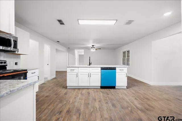 an empty room with wooden floor chandelier and windows