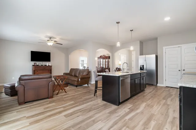 a living room with furniture a flat screen tv and kitchen view