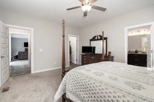 a bedroom with a bed and a flat tv screen on dresser