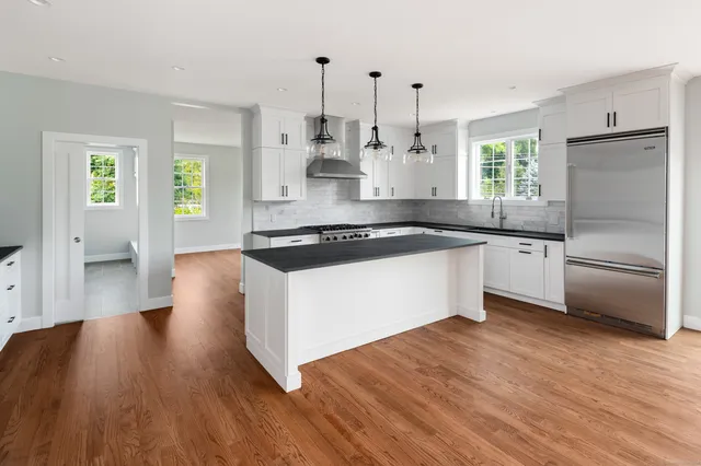 a kitchen with stainless steel appliances a refrigerator a sink dishwasher a stove and white countertops with wooden floor