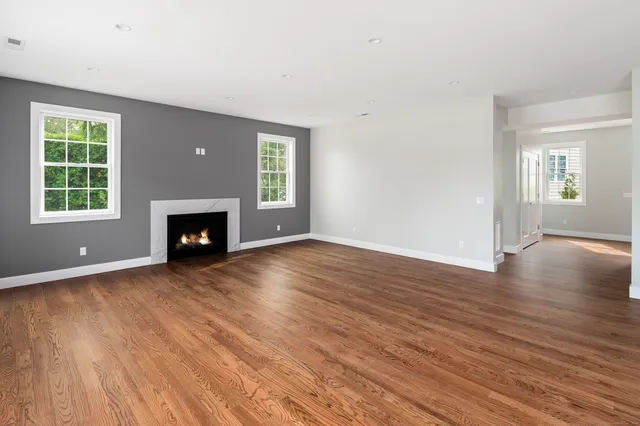 an empty room with wooden floor a fireplace and windows