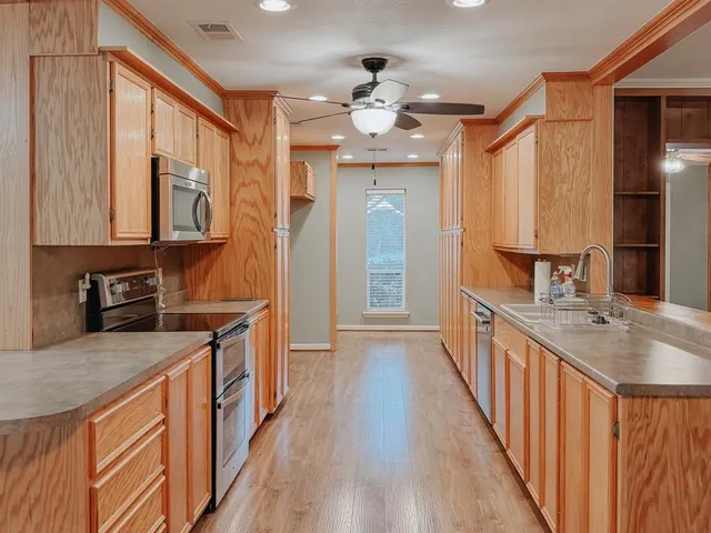 a kitchen with stainless steel appliances granite countertop hardwood floor sink stove and wooden cabinets