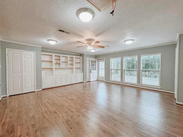 a view of an empty room with a window and wooden floor