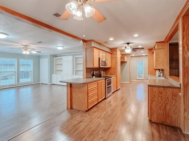 a large kitchen with stainless steel appliances kitchen island a large counter top and a wooden floors