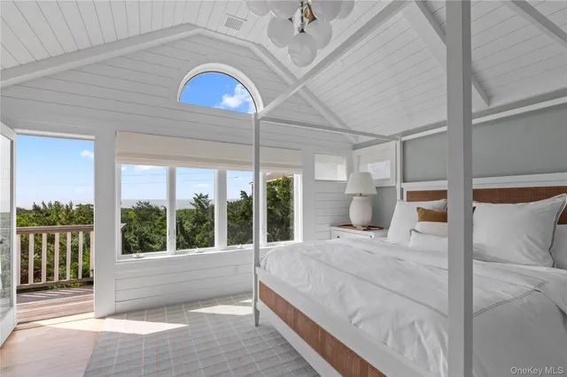 a bedroom with a large bed and a large window with balcony view