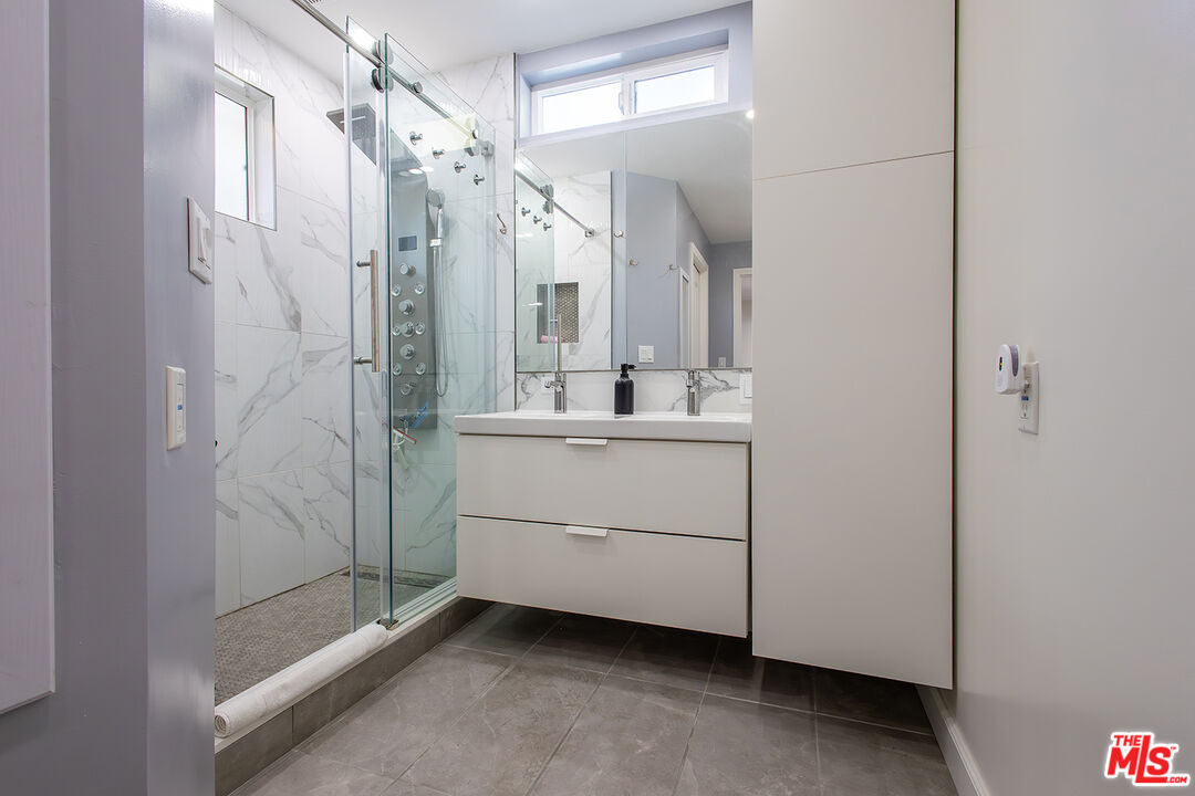 5123 Noble Avenue Sherman Oaks, CA 91403 - Photo 12 of 22 a bathroom with a shower a sink and a mirror