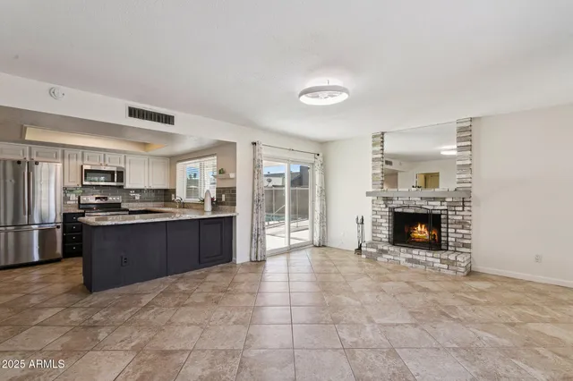 a large white kitchen with granite countertop a stove top oven a sink dishwasher and a fireplace