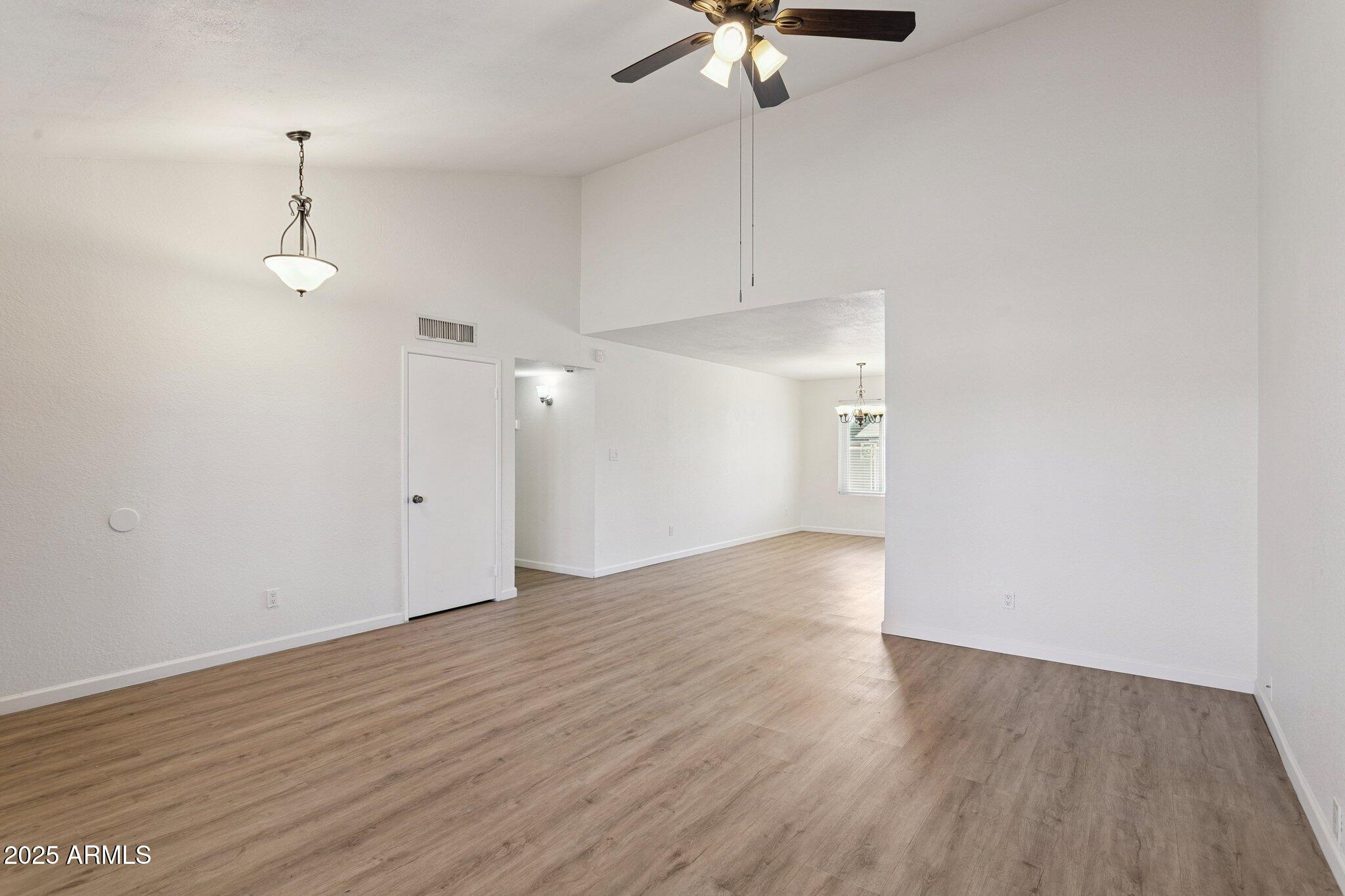 4915 East Everett Drive Scottsdale, AZ 85254 - Photo 15 of 39 an empty room with wooden floor chandelier fan and windows