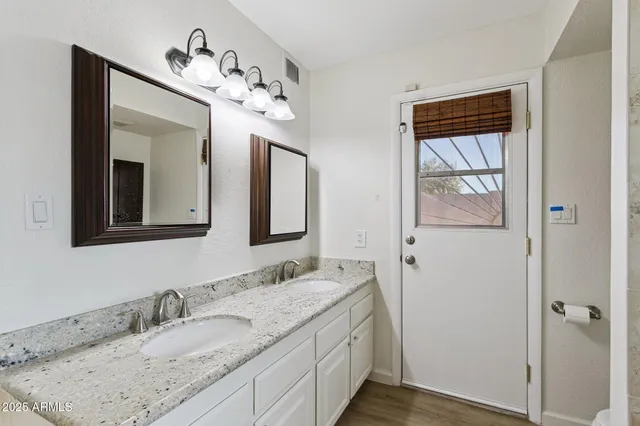 a bathroom with a granite countertop sink vanity and mirror