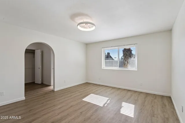 an empty room with wooden floor and windows