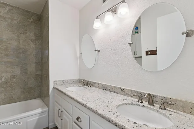 a bathroom with a granite countertop sink mirror toilet and bathtub