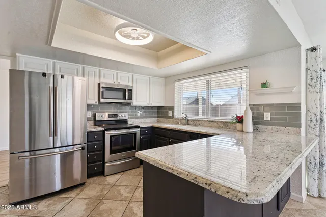 a kitchen with stainless steel appliances granite countertop a sink a stove and a refrigerator
