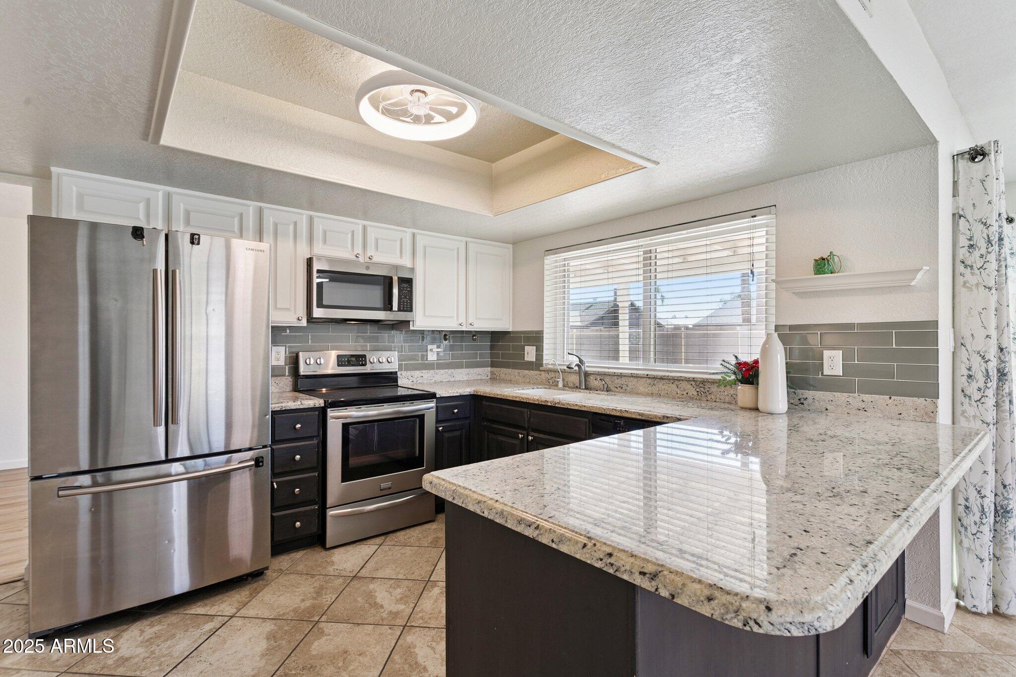 4915 East Everett Drive Scottsdale, AZ 85254 - Photo 3 of 39 a kitchen with stainless steel appliances granite countertop a sink a stove and a refrigerator