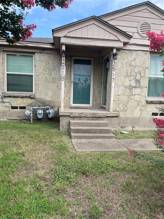 Doorway to property featuring stone siding and a yard