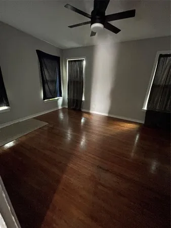 an empty room with wooden floor cabinet and windows