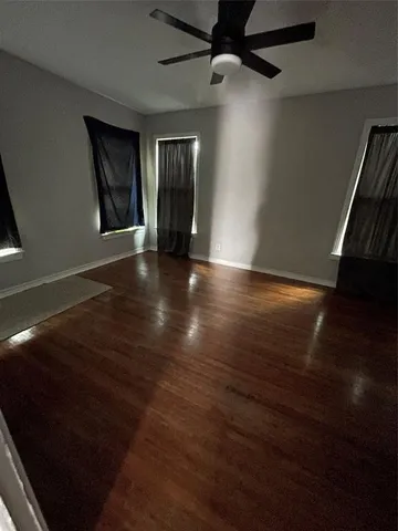 an empty room with wooden floor cabinet and windows
