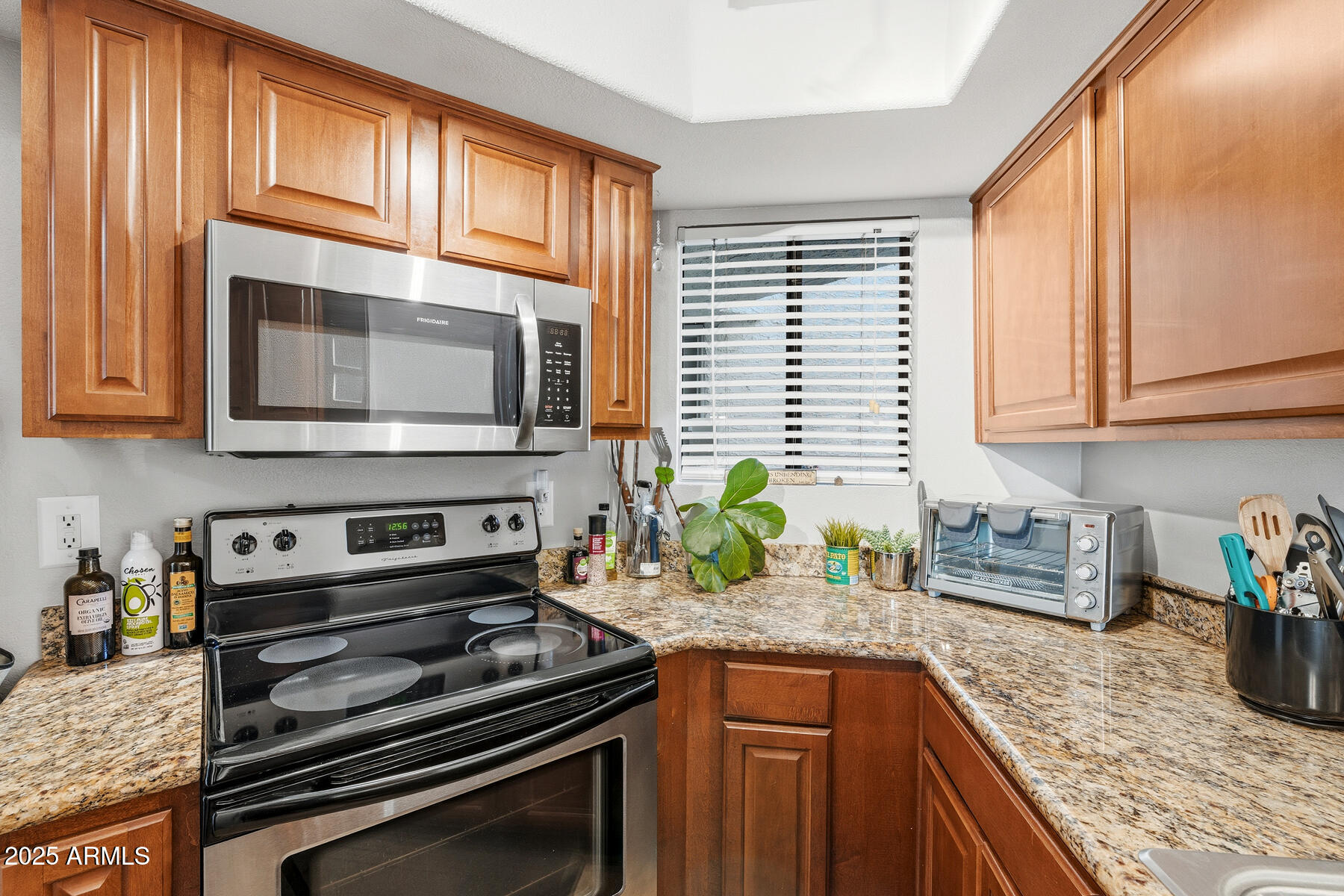 835 North Granite Reef Road, Unit 12 Scottsdale, AZ 85257 - Photo 9 of 23 a kitchen with granite countertop wooden cabinets stainless steel appliances and a window