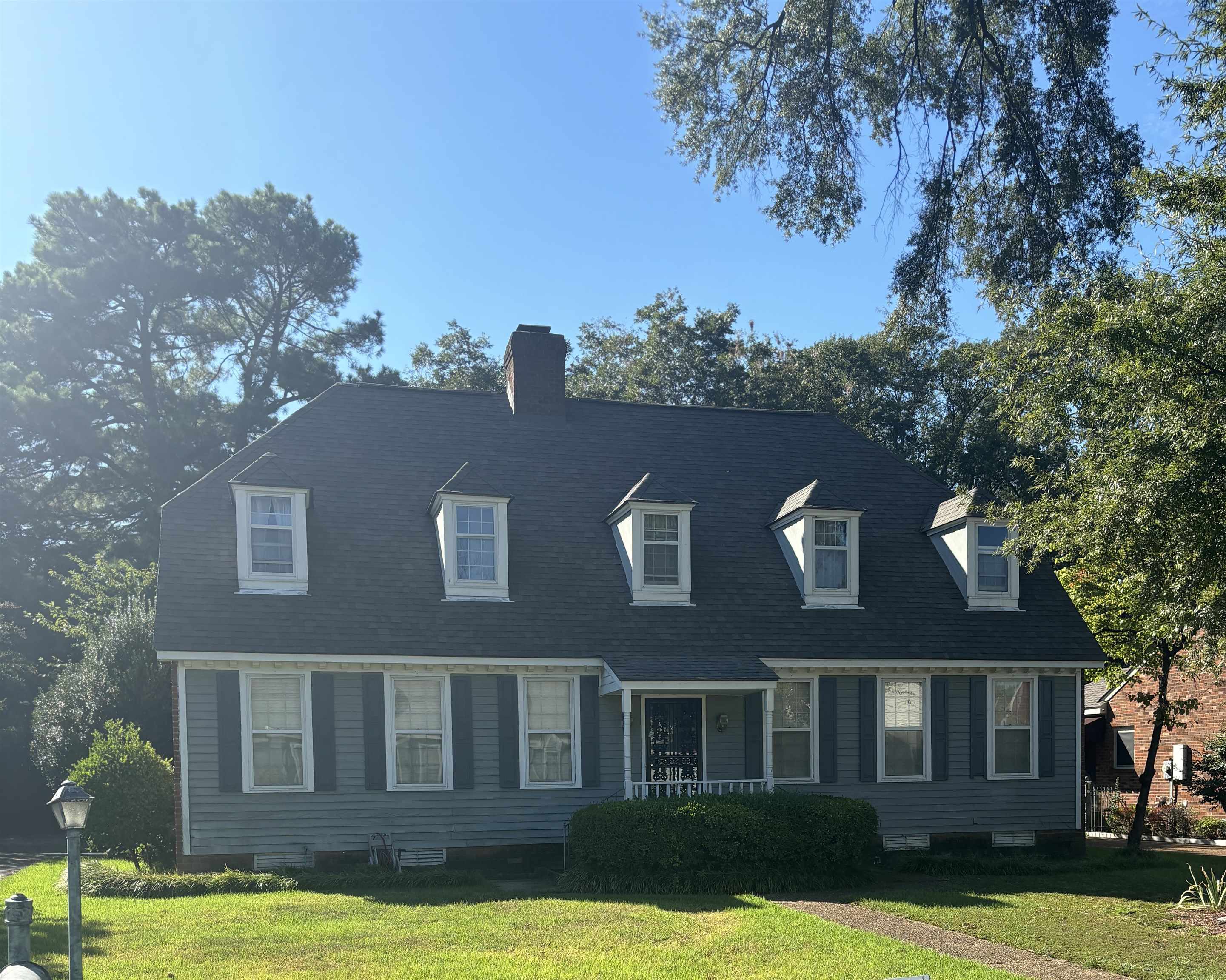 Cape cod house with a front yard, a chimney, a porch, and roof with shingles