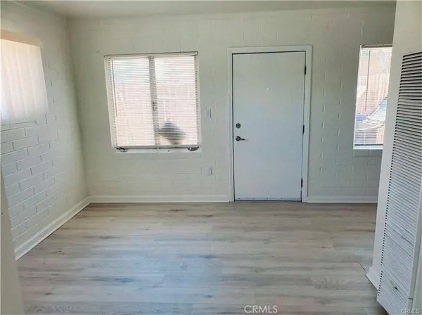 a view of an empty room with wooden floor and window