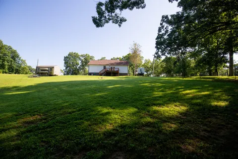 a backyard of a house with table and chairs plants and large tree