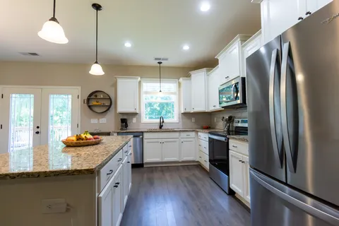 a kitchen with granite countertop stainless steel appliances a center island and a window