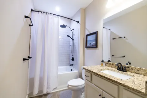 a bathroom with a granite countertop sink toilet and shower