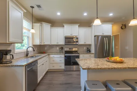 a kitchen with kitchen island granite countertop stainless steel appliances and sink