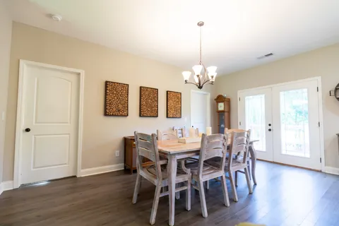 a dining room with wooden floor a chandelier a wooden table and chairs
