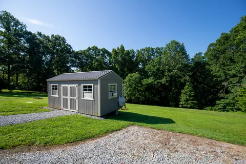 a view of a house with a yard and large tree