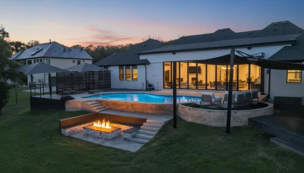 a view of a house with swimming pool lawn chairs and a yard