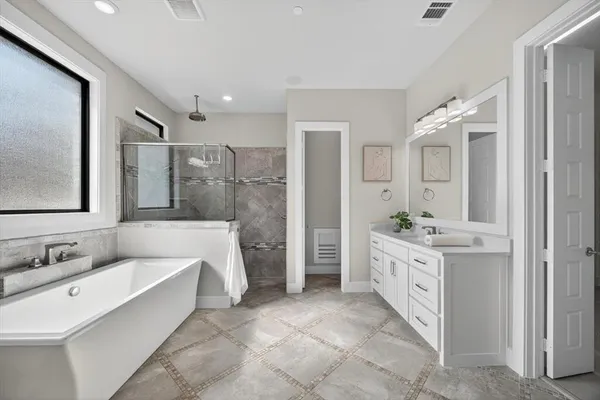 a spacious bathroom with a double vanity sink a mirror a bathtub and shower