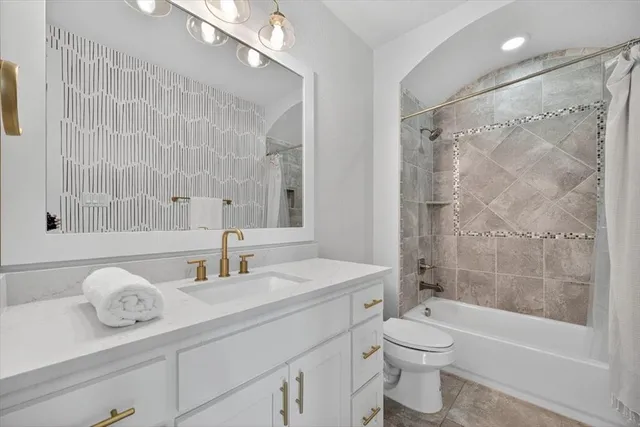 a bathroom with a granite countertop sink a toilet and shower