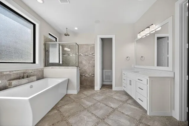 a bathroom with a tub a sink double vanity and a mirror