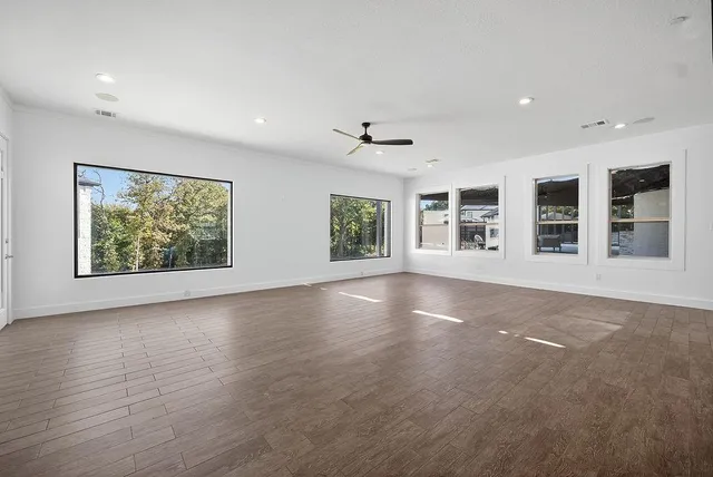 a view of an empty room with a window and wooden floor