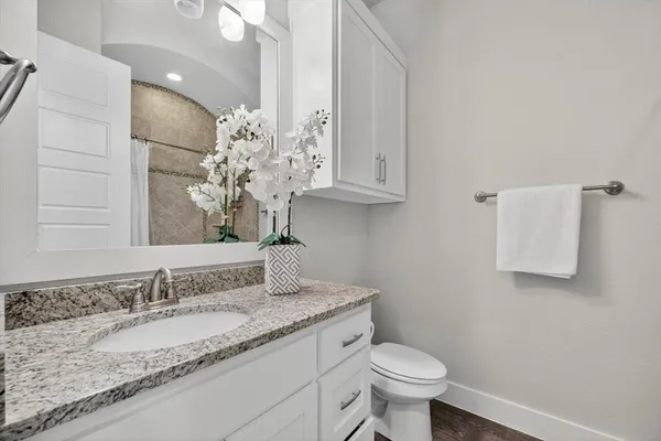 a bathroom with a granite countertop sink and a toilet