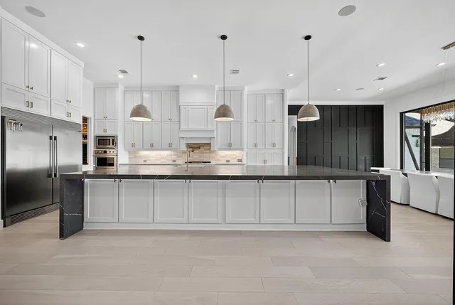 a kitchen with kitchen island granite countertop a sink a counter and stainless steel appliances
