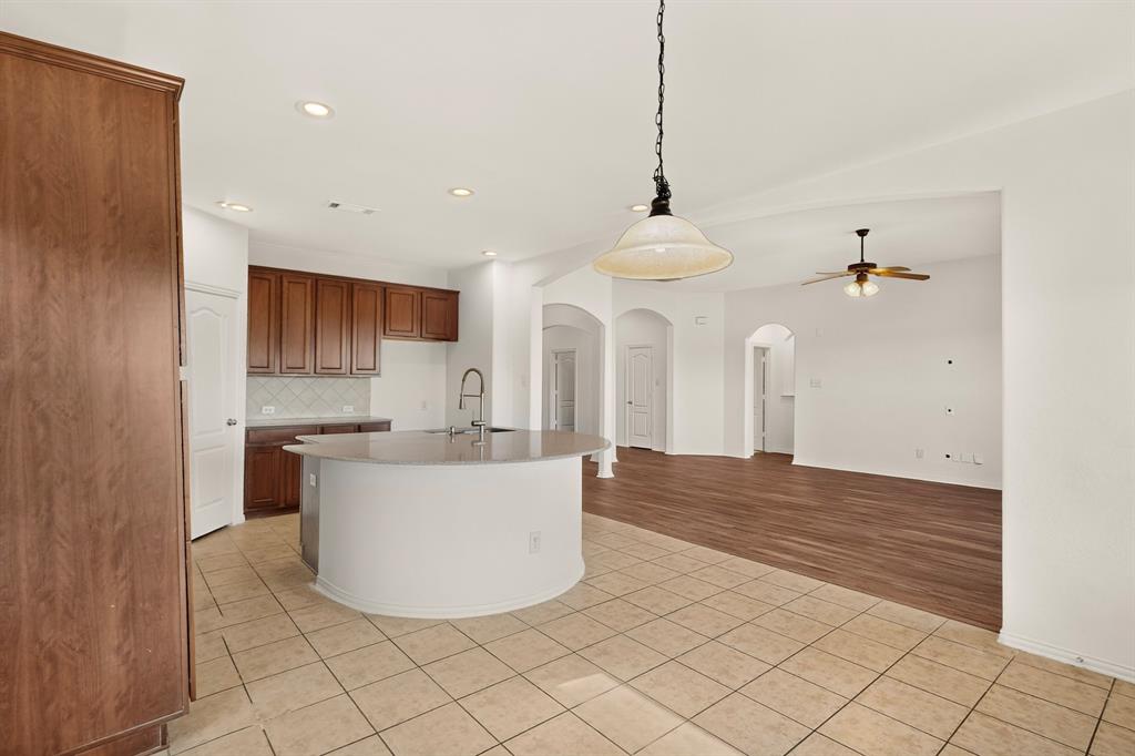 14908 Riverside Drive Little Elm, TX 75068 - Photo 10 of 40 Kitchen featuring wood-finish cabinetry, tile flooring, recessed lighting, and a curved island with an undermount sink