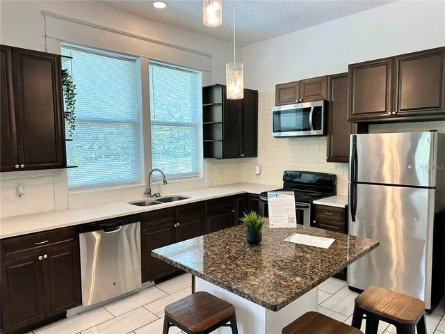 a kitchen with stainless steel appliances granite countertop a sink refrigerator and microwave