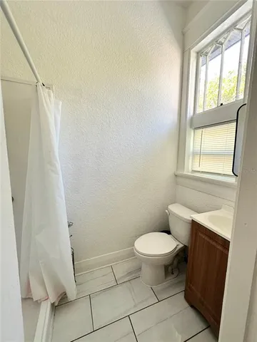 a white toilet sitting next to a window and a shower