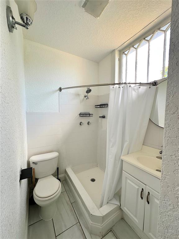 3105 West Spruce Street Tampa, FL 33607 - Photo 36 of 53 a bathroom with a toilet a sink a mirror and a shower