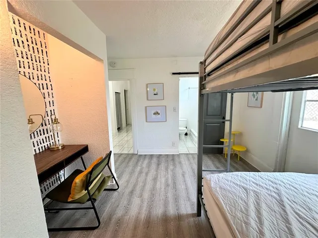 a view of a hallway with wooden floor and a bathroom