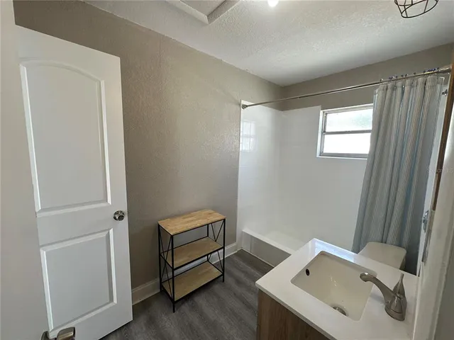 an empty room with wooden floor closet and windows