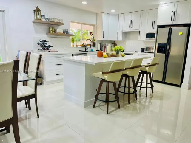 a kitchen with a dining table chairs and refrigerator
